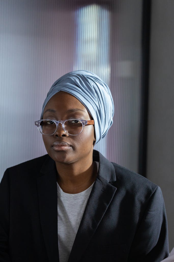 Portrait of a confident businesswoman wearing a blue turban and eyeglasses indoors.